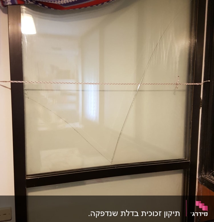 זכוכית שבורה עם סדקים במסגרת חלון שחורה